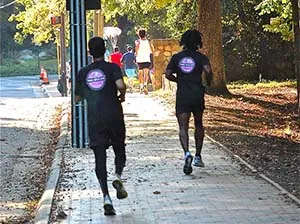 Two male staff running in event back view